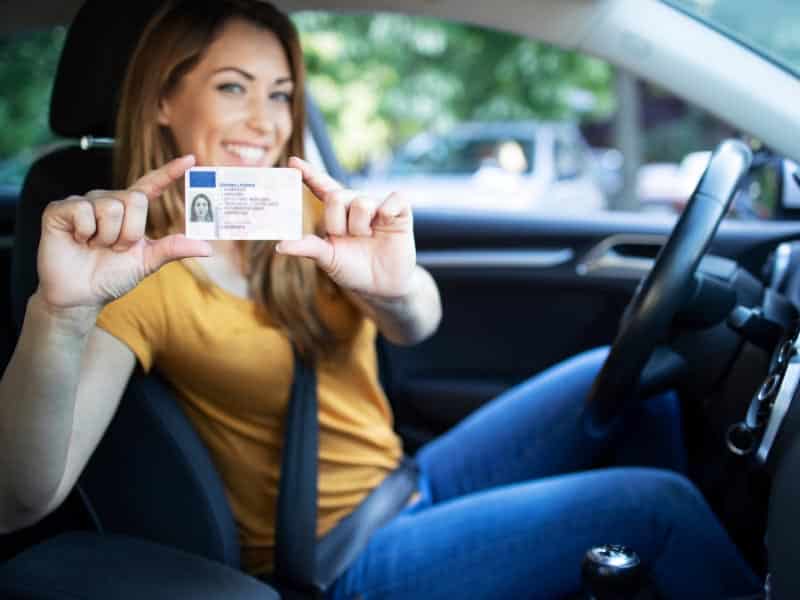 Una mujer sosteniendo un permiso de conducir.